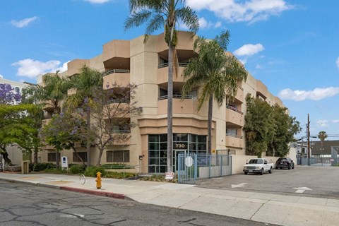 an apartment building with palm trees and a yellow fire hydrant