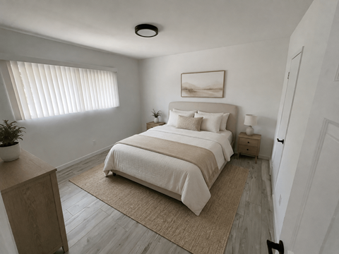 A bedroom with a bed, nightstand, and a plant.
