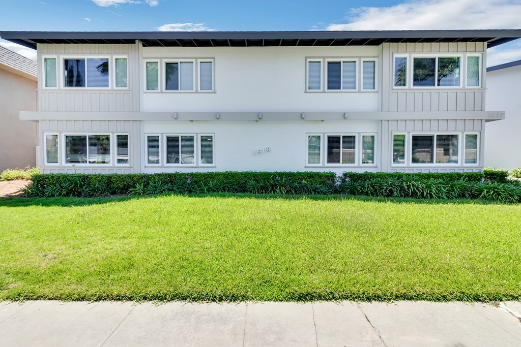 A white building with a green lawn in front.