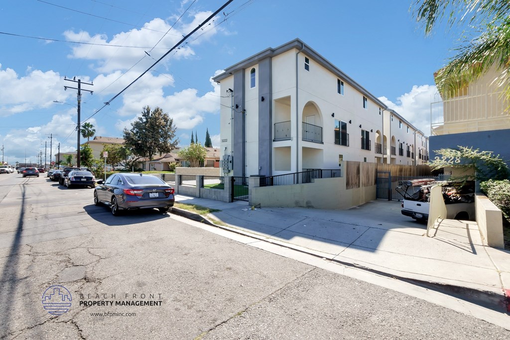 a white building with cars parked in front of it on a street