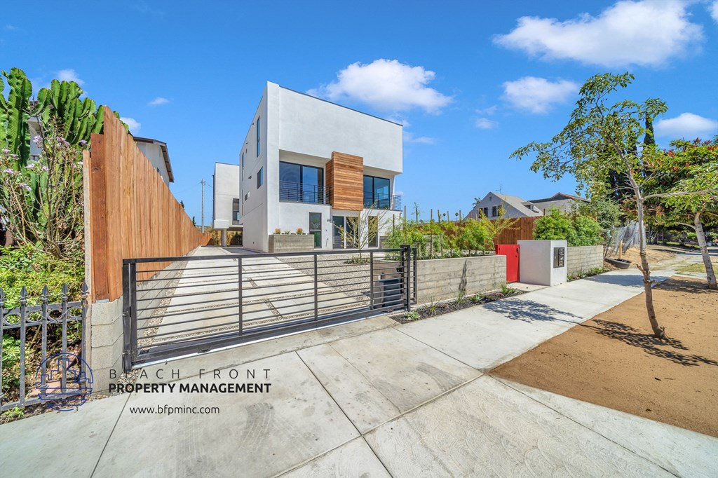 a white house with a fence and a gate on a sidewalk