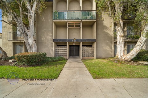 front view of an apartment building with a sidewalk and trees