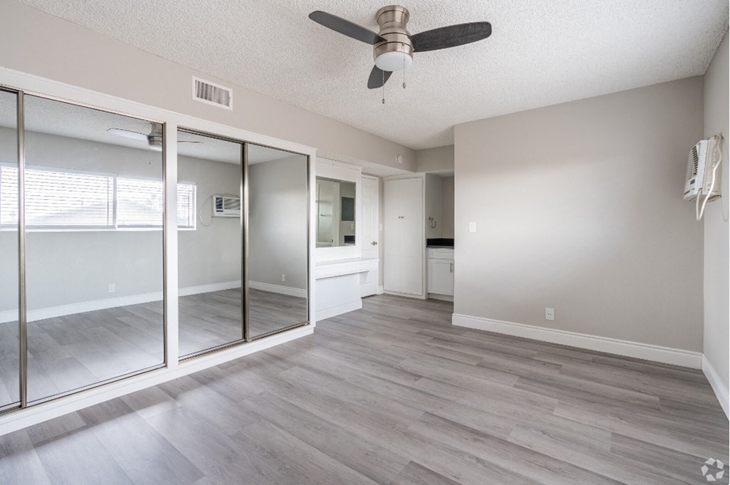 an empty living room with a ceiling fan and sliding glass doors