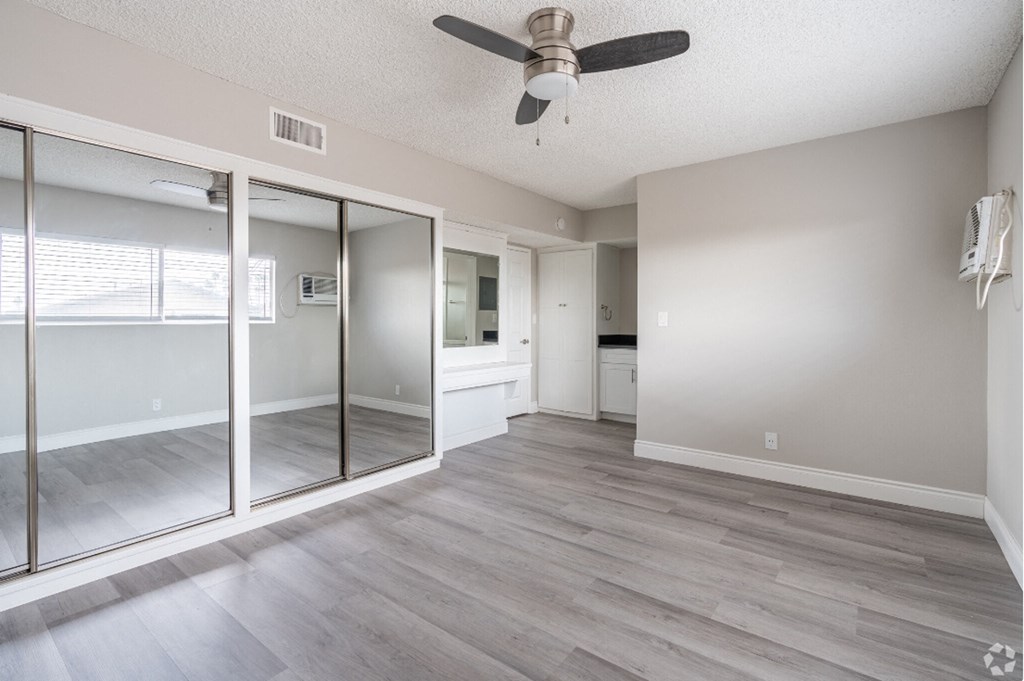 an empty living room with a ceiling fan and sliding glass doors