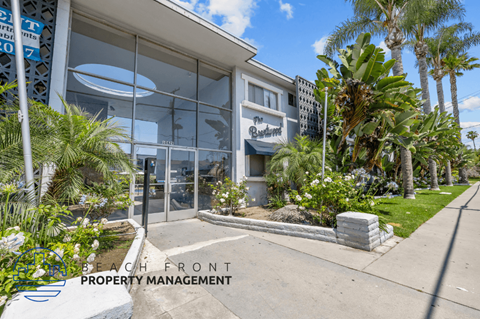 the front of a building with palm trees and a sidewalk