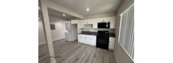 A kitchen with black appliances and white cabinets.