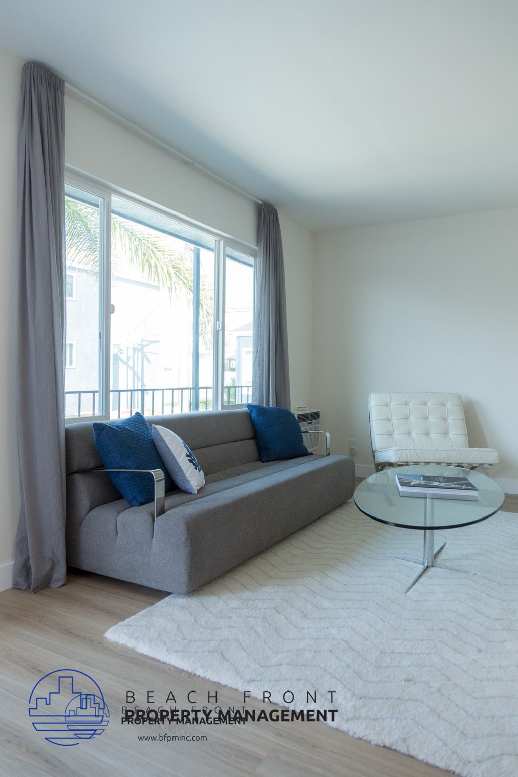A living room with a grey couch and a white chair.