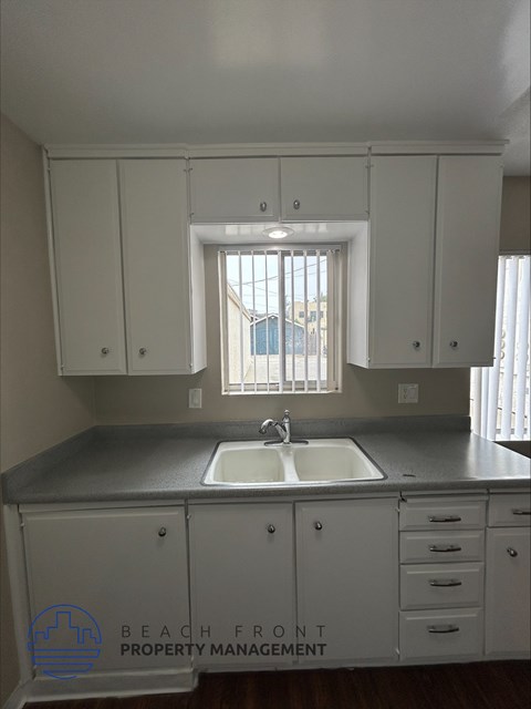 A kitchen with white cabinets and a sink under a window.
