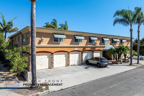 A building with a car parked in front and palm trees around it.