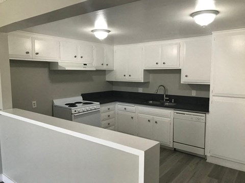 A kitchen with white cabinets and a black countertop.