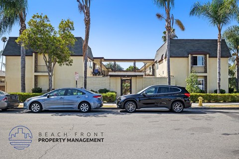 Two cars parked in front of a building with the logo "BEACH FRONT PROPERTY MANAGEMENT" on the ground.