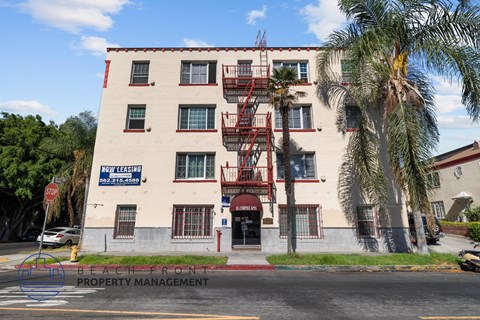 A building with a sign that says "Now Leasing" is in front of some trees.
