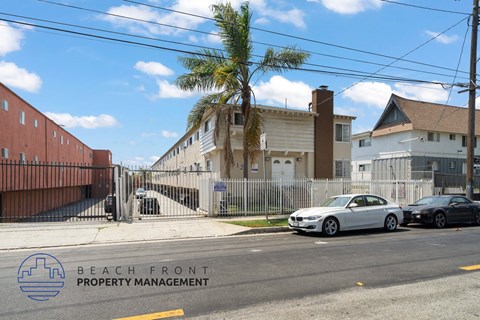 A street view with cars parked on the side and a building with the text