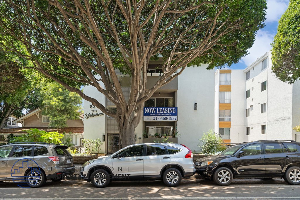A silver car with the word "CONTENT" written on it is parked in front of a building with a "NO LEASING" sign.