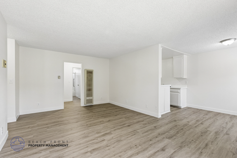 A spacious room with wooden flooring and white walls.