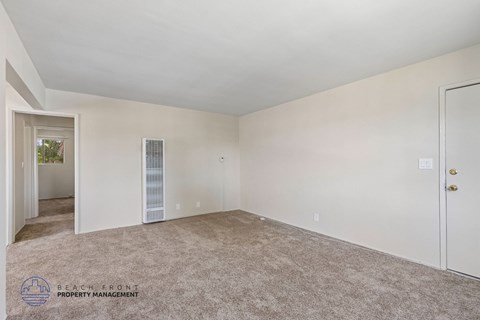 A spacious room with a carpeted floor and a door on the right side.