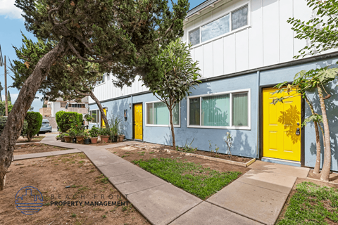 A building with a yellow door is surrounded by greenery.