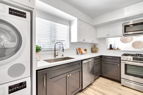 A modern kitchen with a washing machine on the left and a stove on the right.