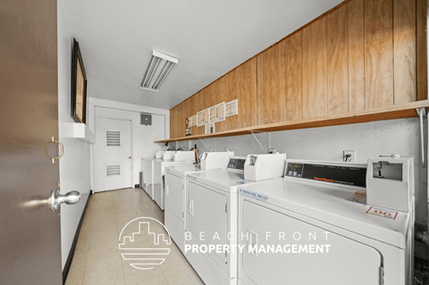 A laundry room with washers and dryers and a logo for Beach Front Property Management.