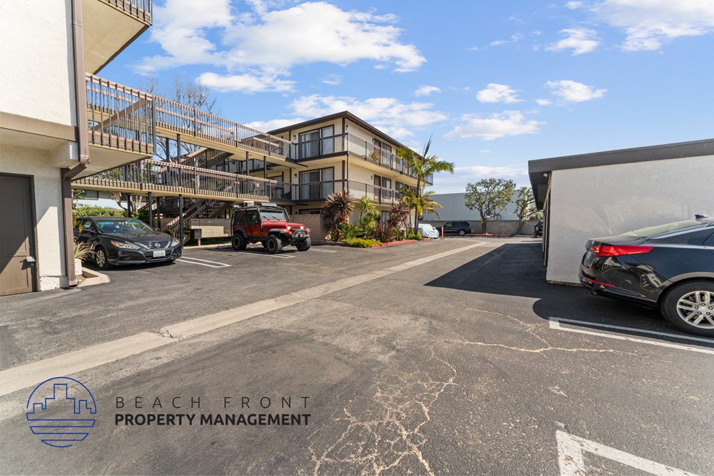 A parking lot with cars and a building in the background with the words Beach Front Property Management.