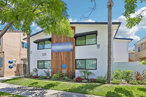 A modern house with a wooden front door and a green lawn.