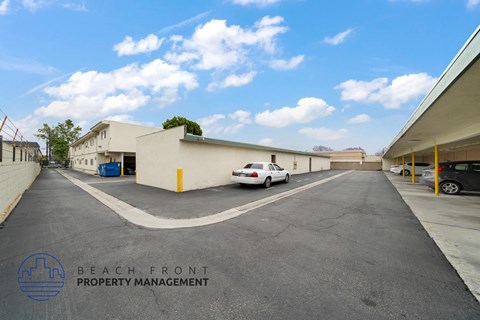 A parking lot with a white car parked in front of a building with the words Beach Front Property Management on it.