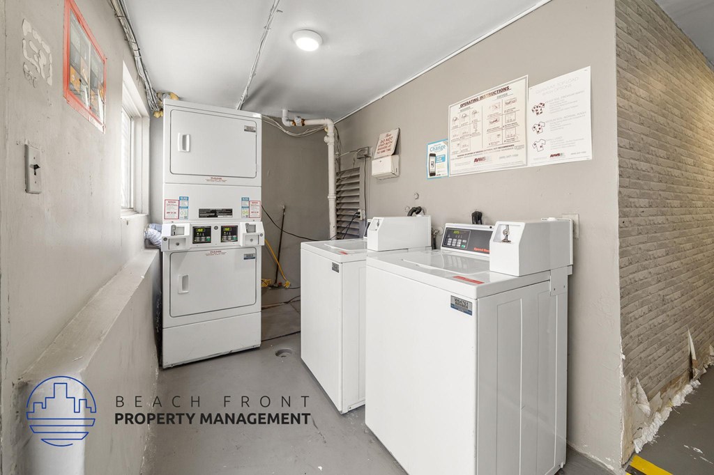 A white fridge and freezer are in a room with a sign that says Beach Front Property Management.