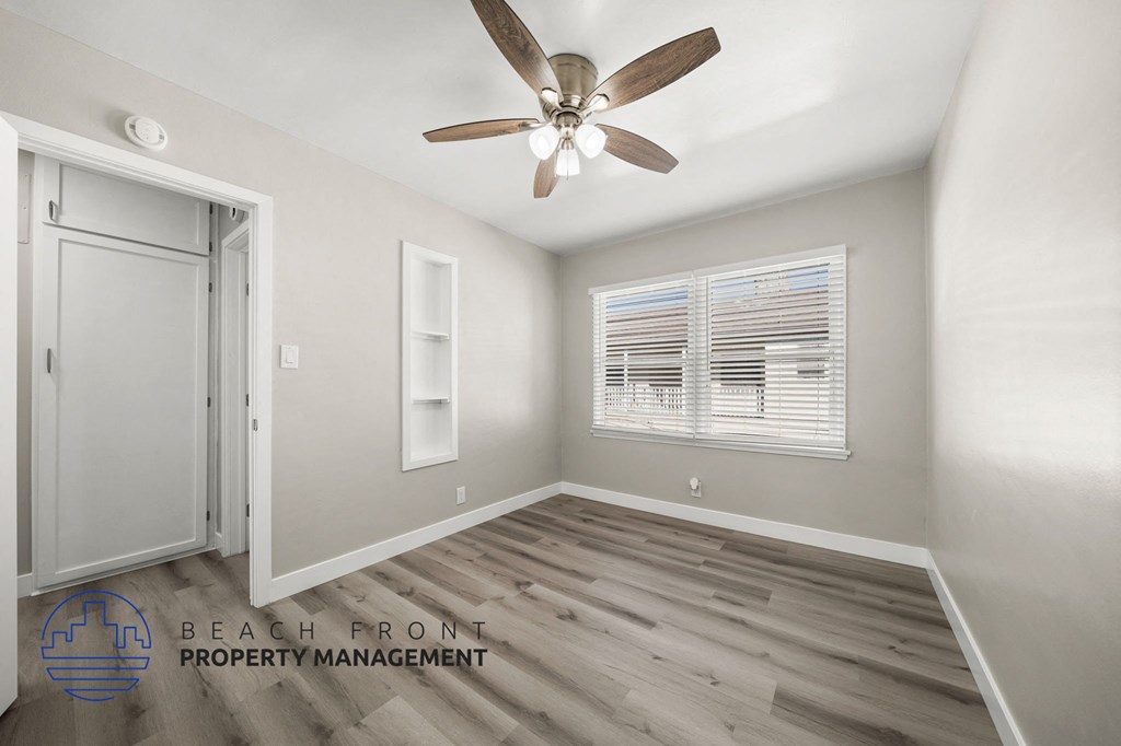 A room with a ceiling fan and a window with blinds.