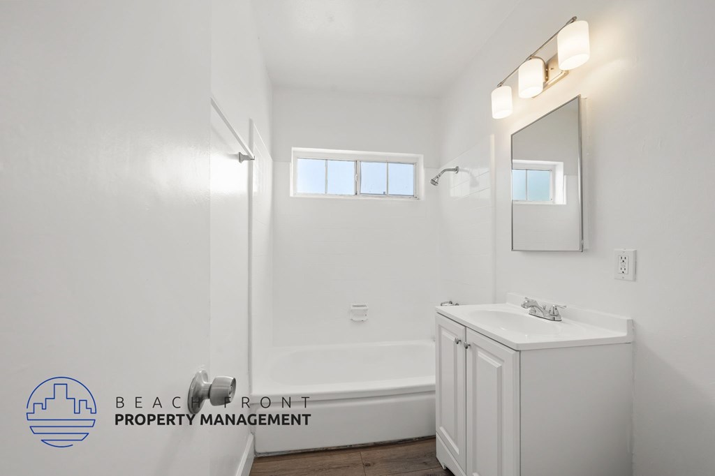 A white bathroom with a large mirror and a bathtub.