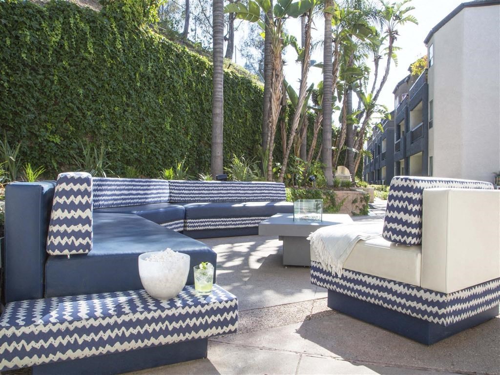 a lounge area with blue and white furniture and a wall of trees