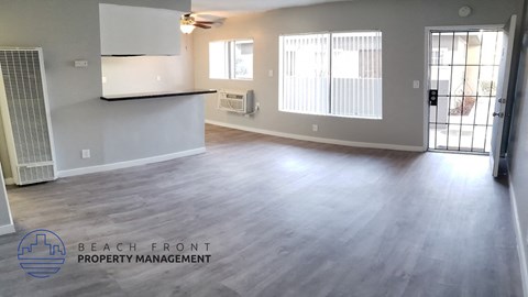 A spacious room with a ceiling fan and sliding glass doors leading to a balcony.