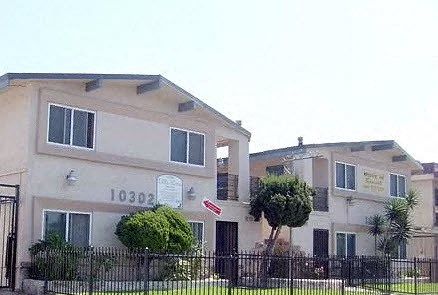 an apartment building with a yard and a fence