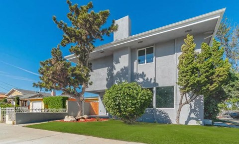 a house with a lawn and trees in front of it