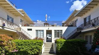 the front of a white house with a balcony and a staircase