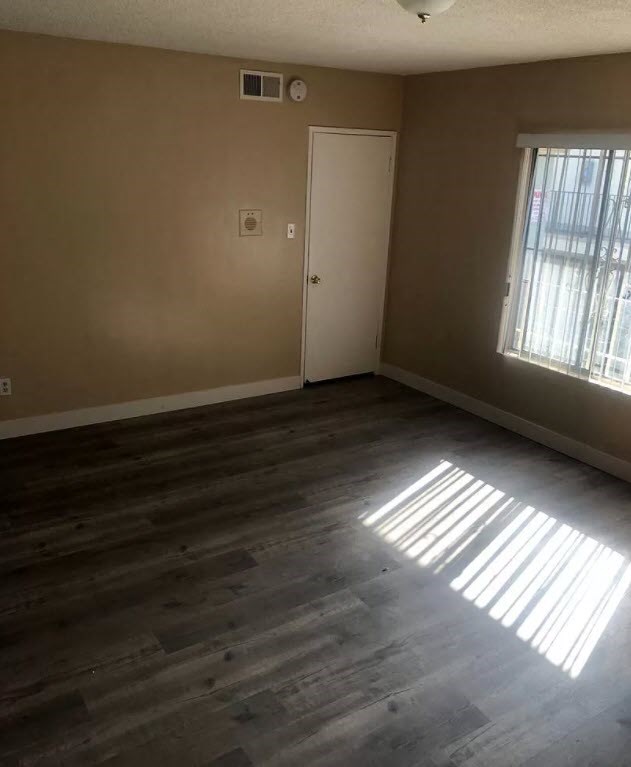 an empty living room with wooden floors and a window