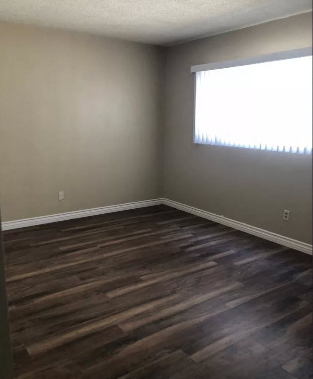 an empty room with wooden floors and a window