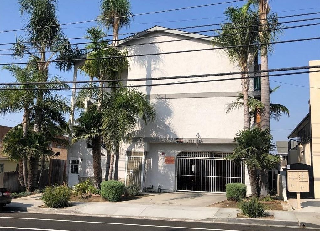 a white building with a gate and palm trees