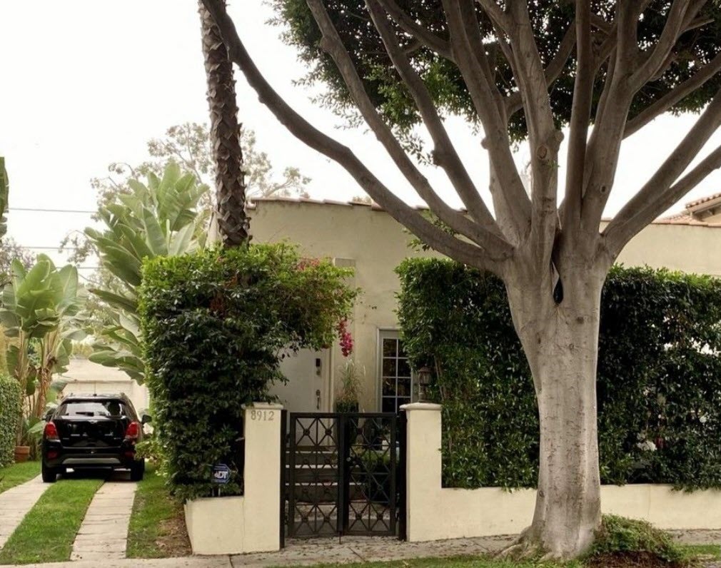 a car is parked in front of a house with a tree