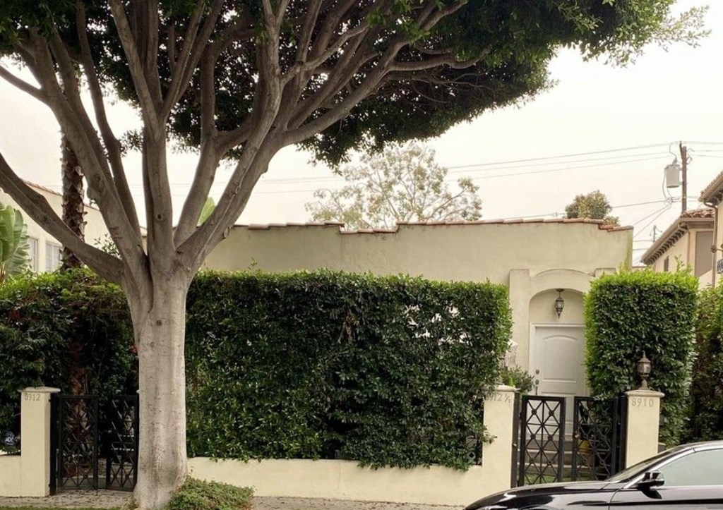 a car parked in front of a house with a tree