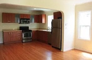 a kitchen with wooden floors and a stainless steel refrigerator