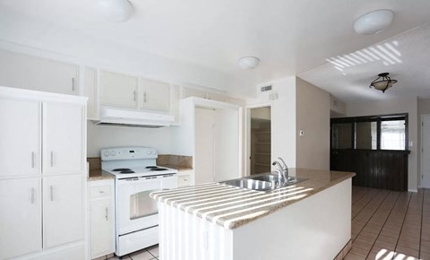 an empty kitchen with white appliances and a sink