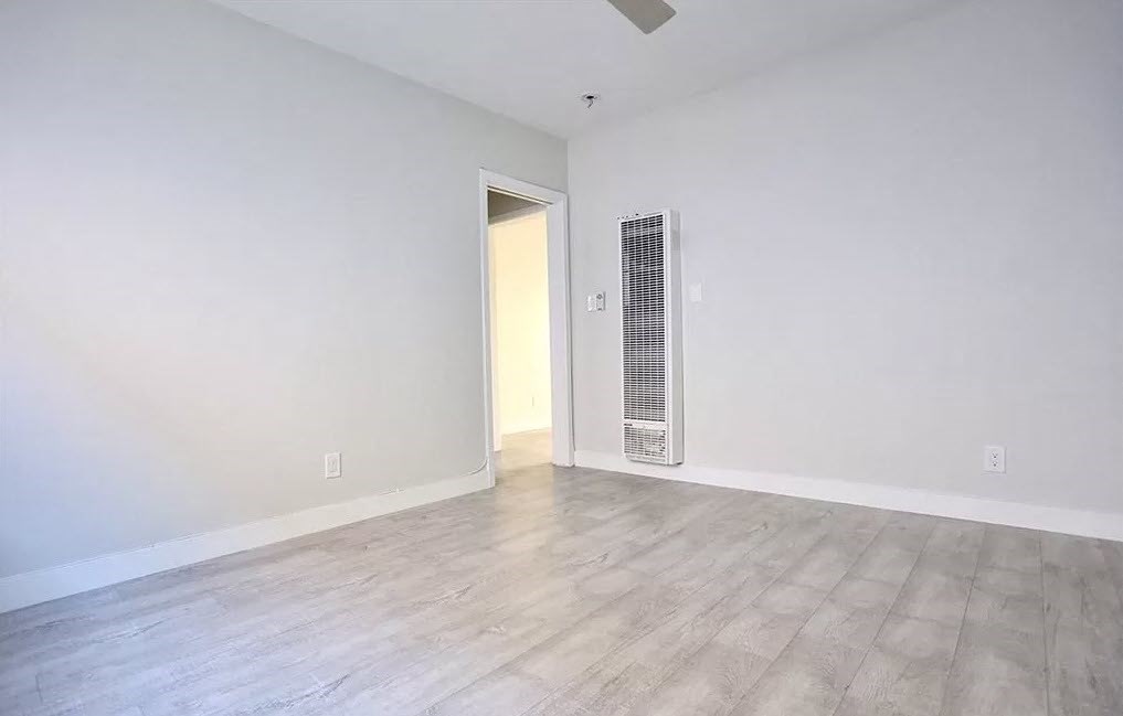 an empty living room with white walls and wood floors