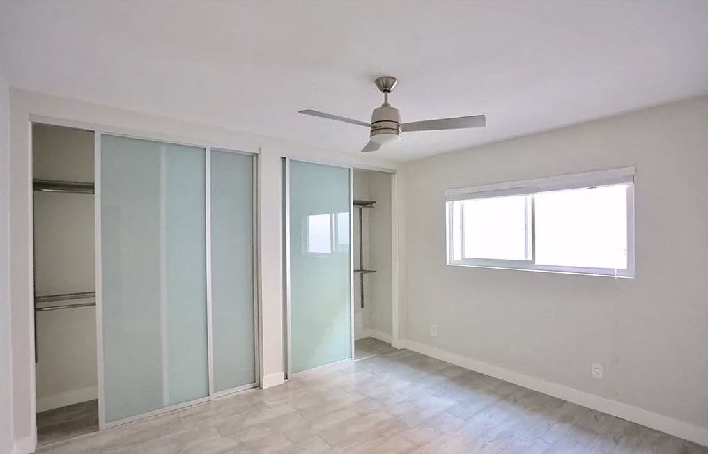 an empty room with sliding glass doors and a ceiling fan