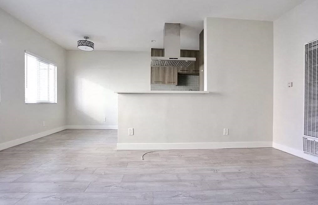 an empty living room with a kitchen in it