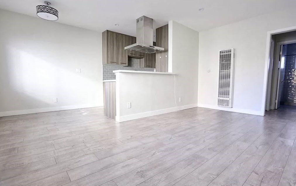 an empty living room with white walls and wood floors