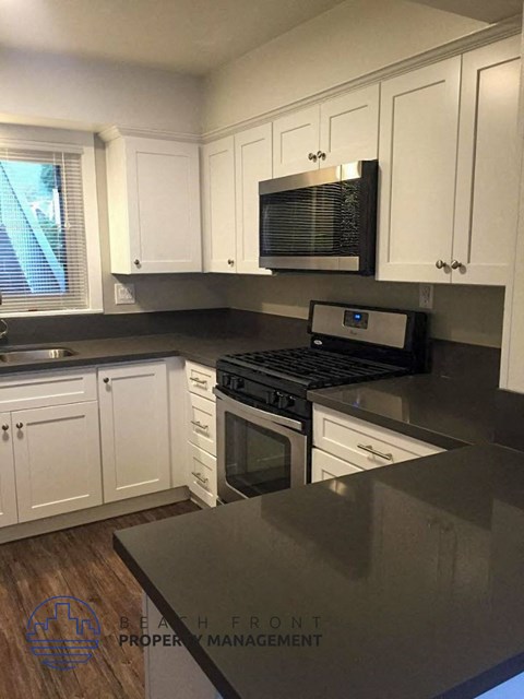 A kitchen with white cabinets and a black stove top oven.