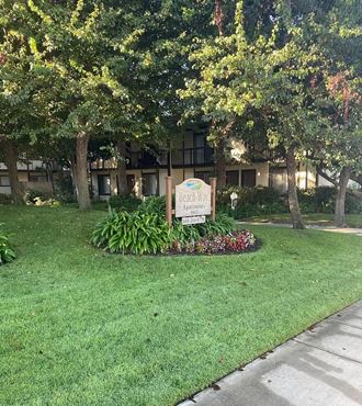 a lawn with a sign in front of an apartment building