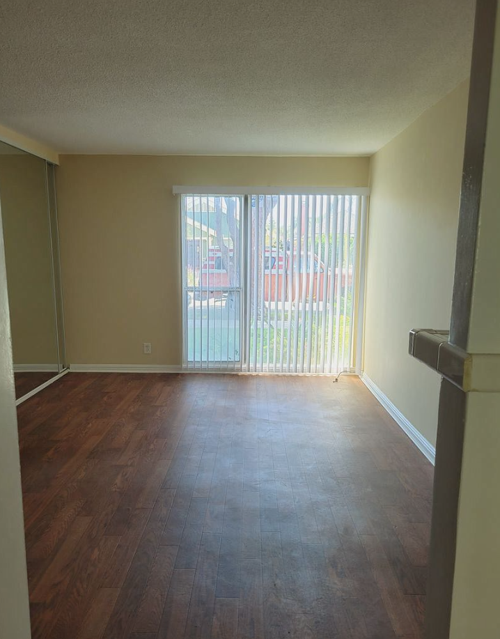 an empty living room with wood floors and a sliding glass door