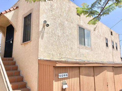 the side of a building with a wooden gate and stairs