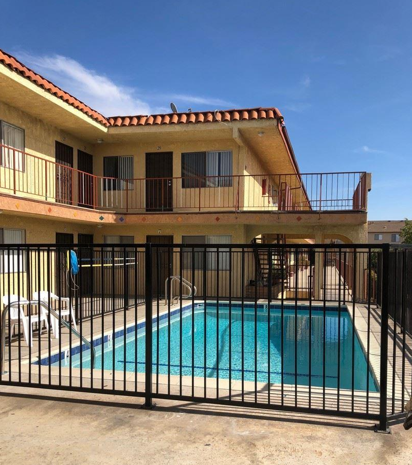 a swimming pool in front of a house with a black fence